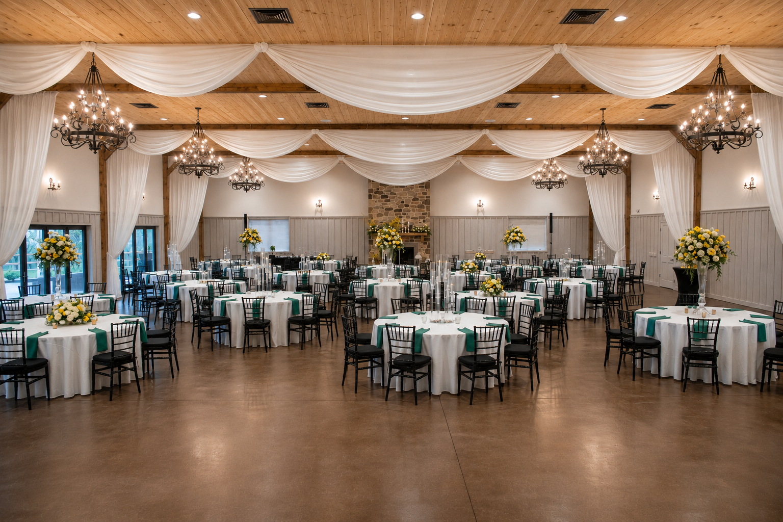 The banquet hall set with round tables, chandeliers, and draped ceiling fabric